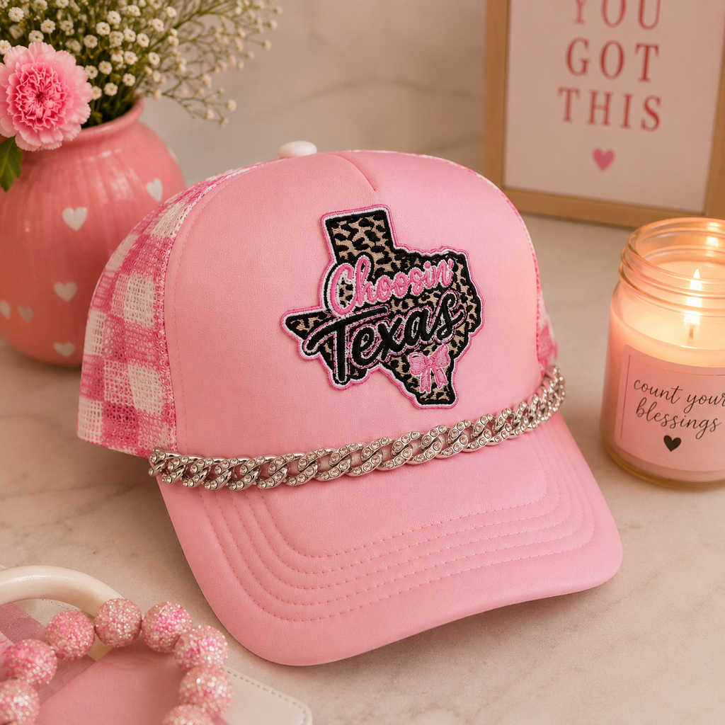 Pink Choosin' Texas rhinestone trucker hat - lifestyle shot with pink accessories and candle